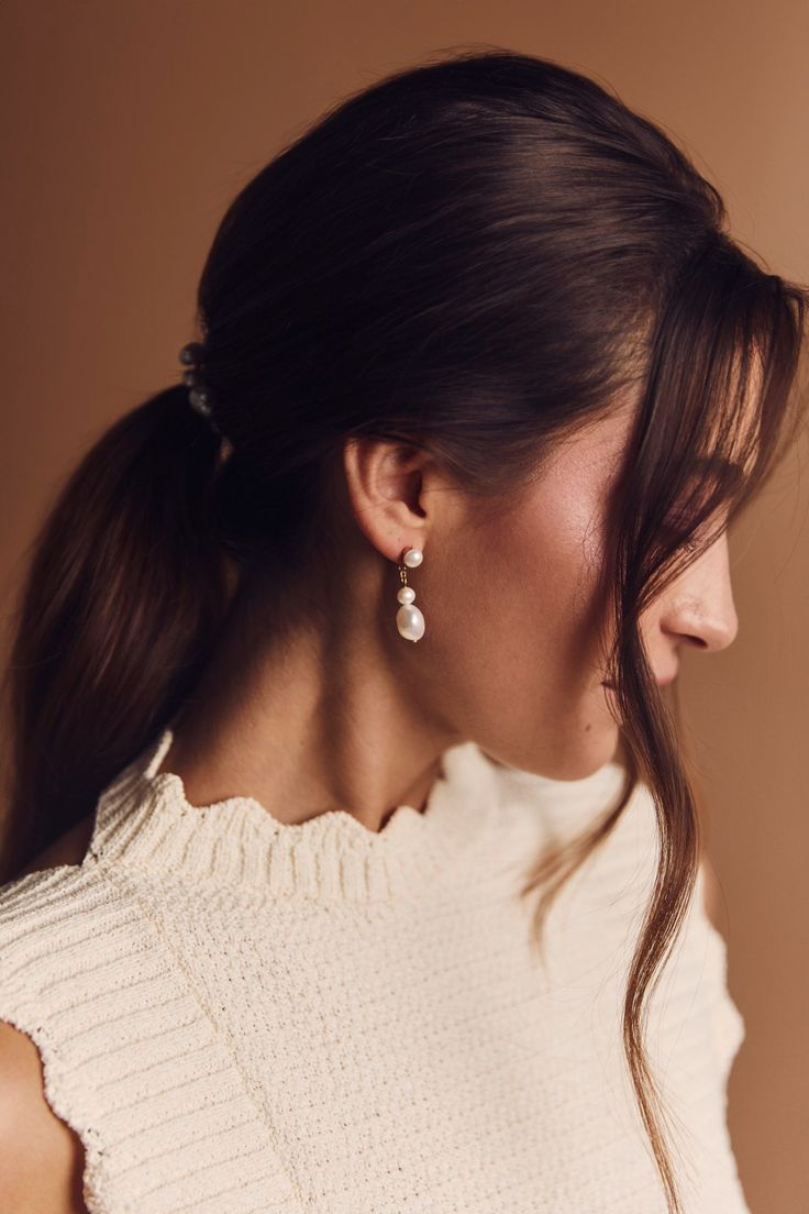 a woman in a white sweater and earrings