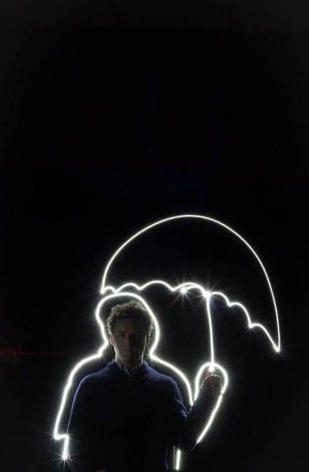 a man standing in the dark with an umbrella drawn on his face and light painting