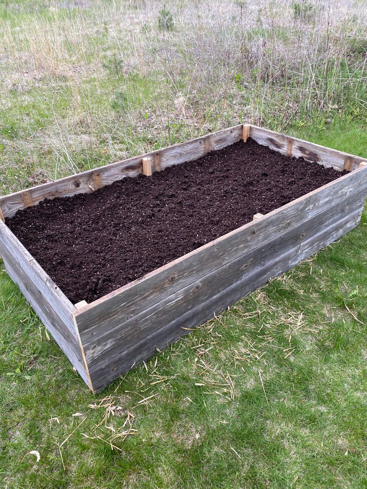 a wooden box filled with dirt in the grass