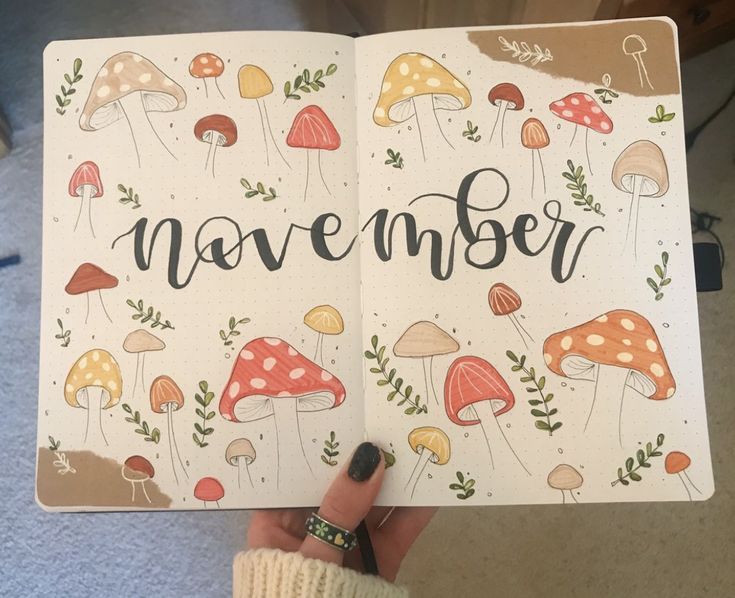 someone holding up a notebook with the word november written on it and mushrooms all over them