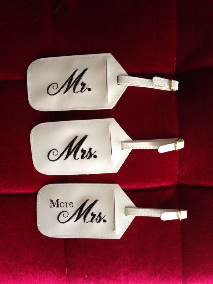 three white luggage tags with the words mr and mrs on them sitting on a red velvet surface