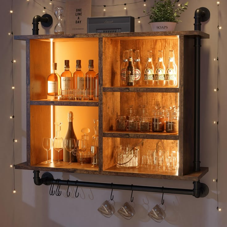 an open cabinet with liquor bottles and glasses on the shelves in front of it is lit by string lights