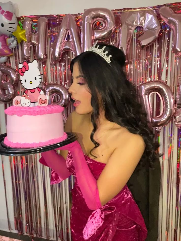 a woman in a pink dress holding a hello kitty cake