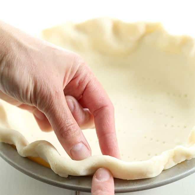 a person is pressing the dough into a pie crust on top of a metal pan