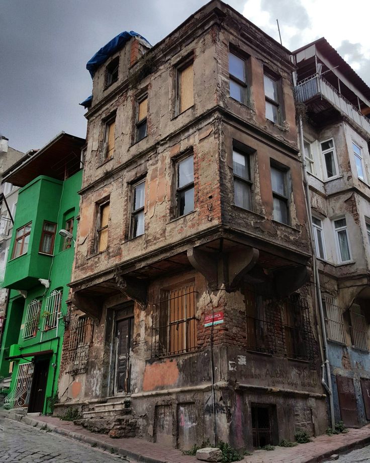 an old building in the middle of two different colored buildings with windows and balconies