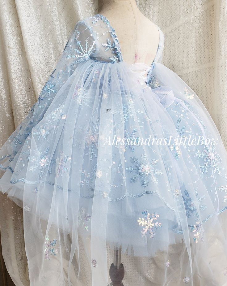 Ice Queen Couture Dress Made with a beautiful sequined snowflake mesh in light blue and irredescent snowflakes, long sheer sleeves, a criss cross back making it super adjustable with voluminous tulle skirt. All dresses are completely lined for comfort. Available in light pink upon request Custom colors and sizes welcomed Handmade to order in the USA Long Sleeve Tulle Dress For Holidays, Blue Princess Dress In Glitter Tulle, Winter Princess Dress In Tulle For Dress-up, Winter Princess Dress For Dress-up, Winter Tulle Princess Dress For Dress-up, Princess Style Blue Glitter Tulle Dress, Light Blue Long Sleeve Princess Dress For Party, Light Blue Long Sleeve Princess Party Dress, Long Sleeve Tulle Tutu Dress For Pageants