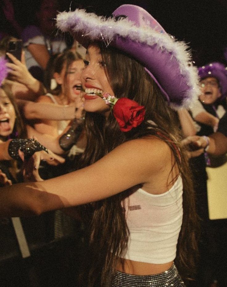 a woman wearing a purple hat with feathers on it's head at a party