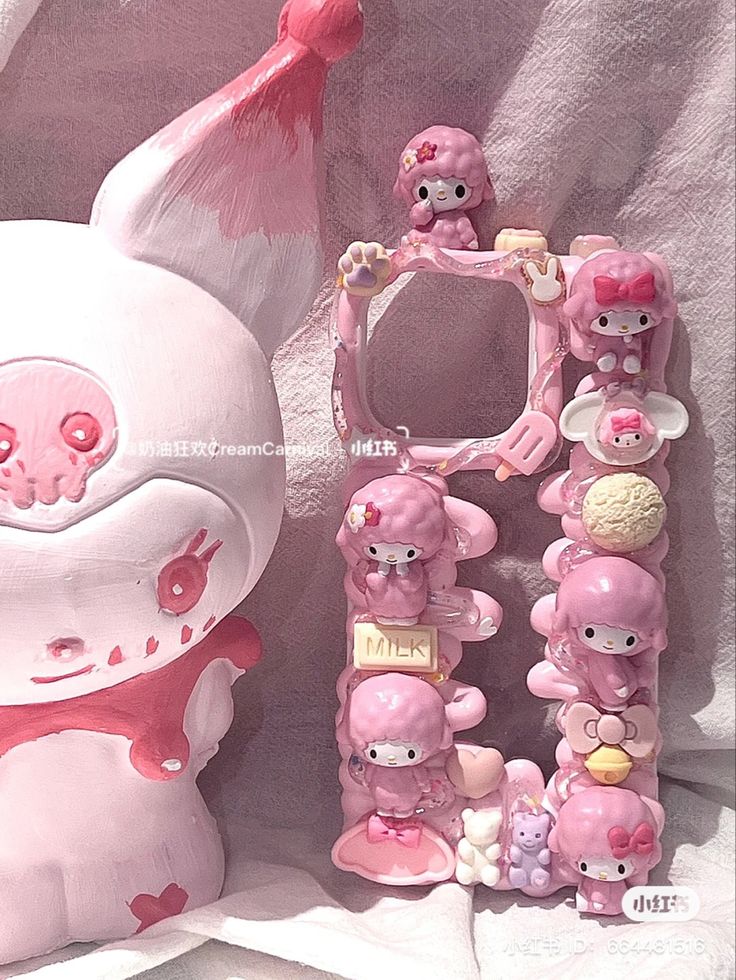 a pink hello kitty cell phone case next to a white teddy bear and other items