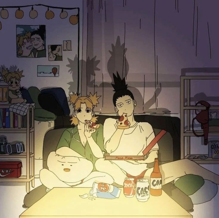 two people sitting on a couch eating pizza and drinking beer in the living room at night