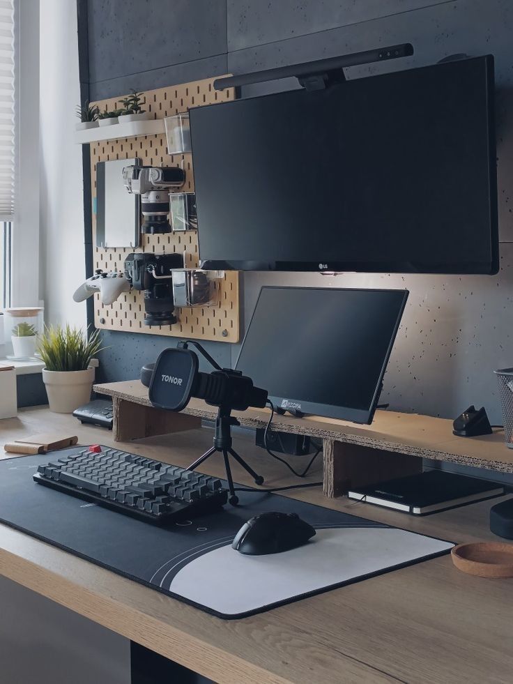 a desk with a computer monitor, keyboard and mouse on it in front of a flat screen tv