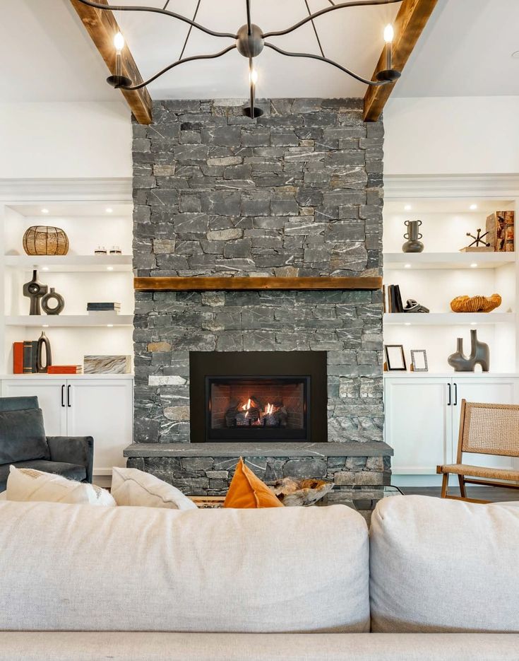 a living room filled with furniture and a fire place in front of a stone fireplace