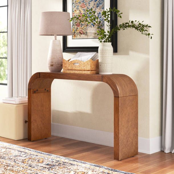 a wooden table with a lamp on top of it next to a rug and window