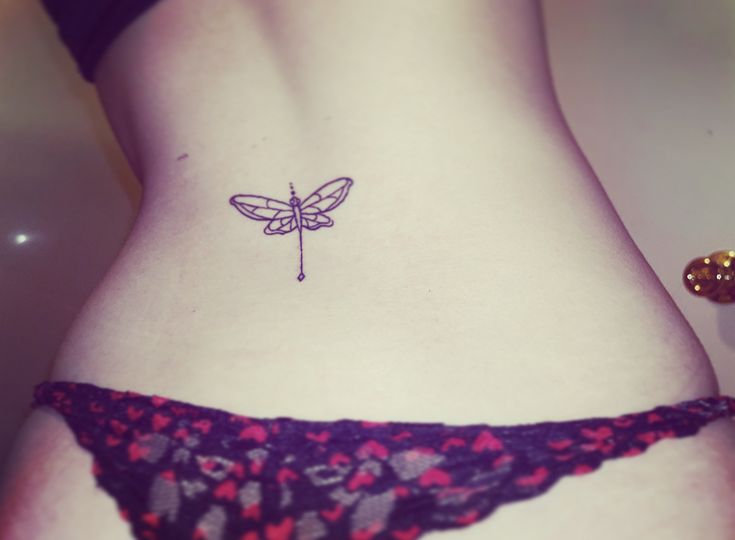 a woman's stomach with a small tattoo of a dragonfly on the side