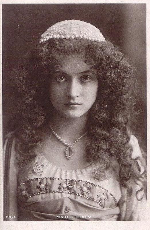 an old photo of a woman with curly hair wearing a hat and pearls on her head