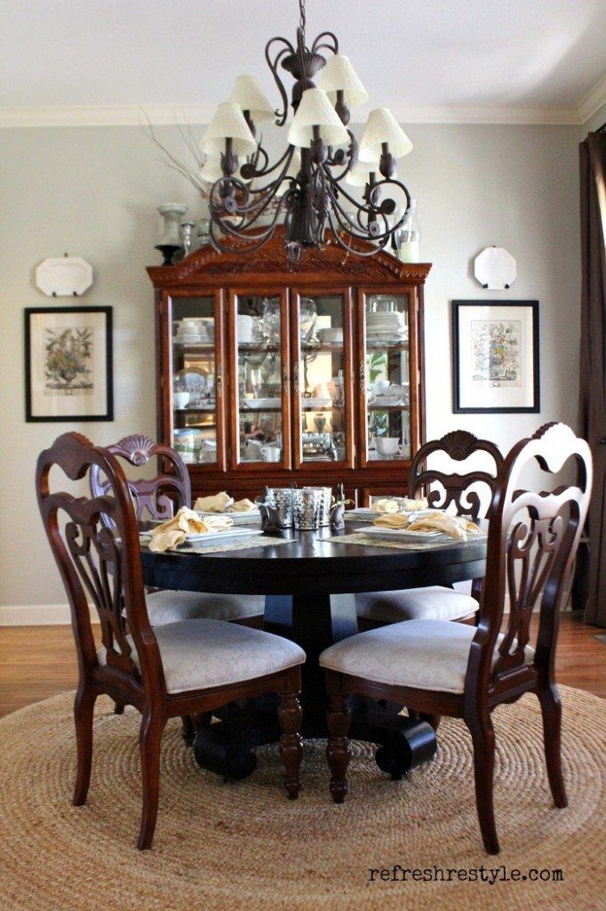 a dinning room table with chairs and a china cabinet in the corner behind it