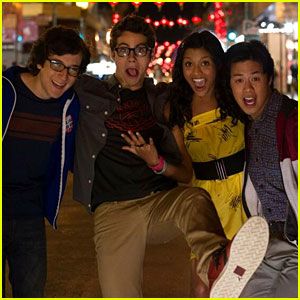 four young people posing for a photo in front of a city street with christmas lights