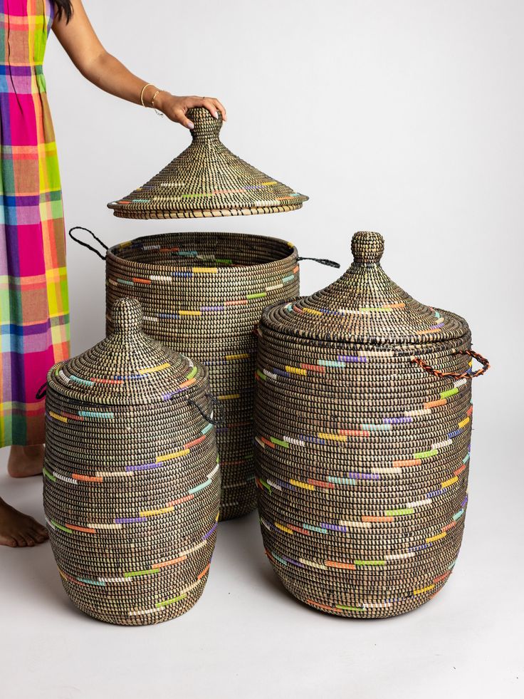 a woman is standing next to three woven baskets with lids and handles, one has a lid on the top