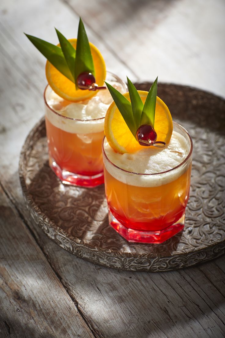 two glasses filled with drinks sitting on top of a plate