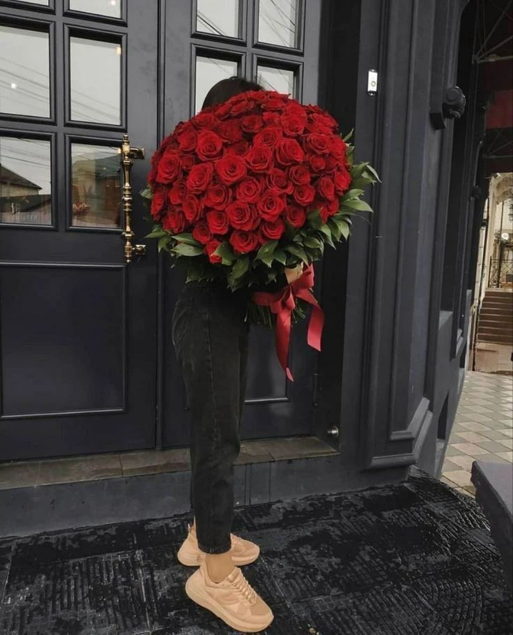 a person holding a large bouquet of red roses