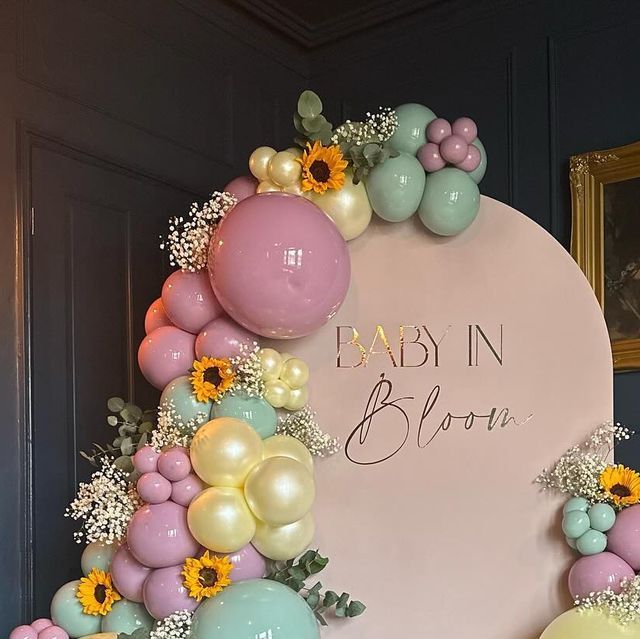 a baby in bloom sign surrounded by balloons and flowers