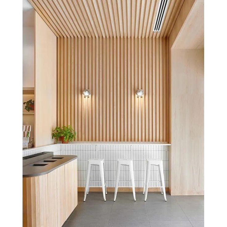 three white stools in front of a counter with two plants on top of it