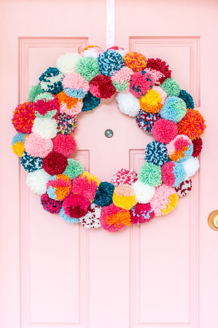 a pink door with a colorful wreath on it