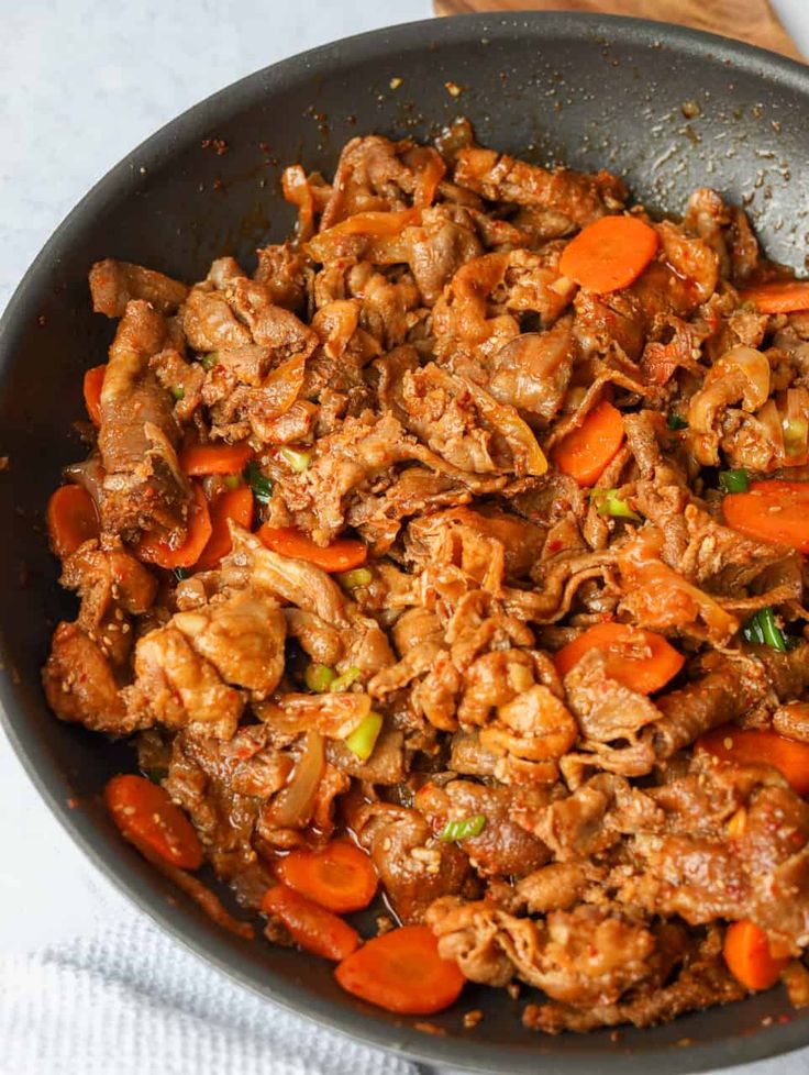 a pan filled with meat and carrots on top of a table