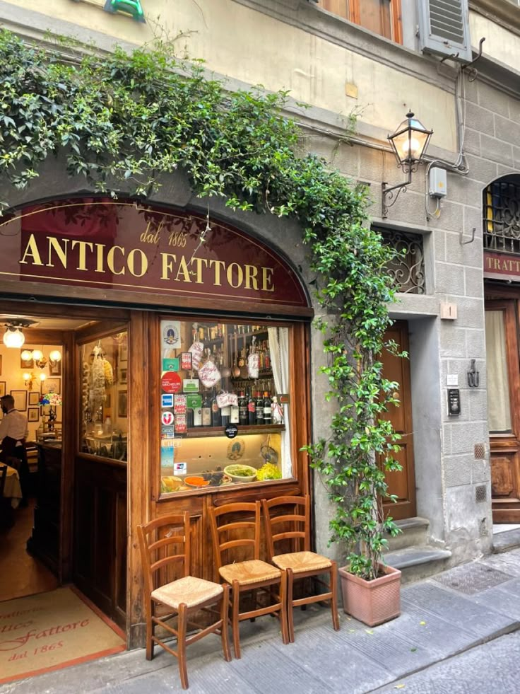 the entrance to an italian restaurant with wooden chairs and tables in front of it on a city street