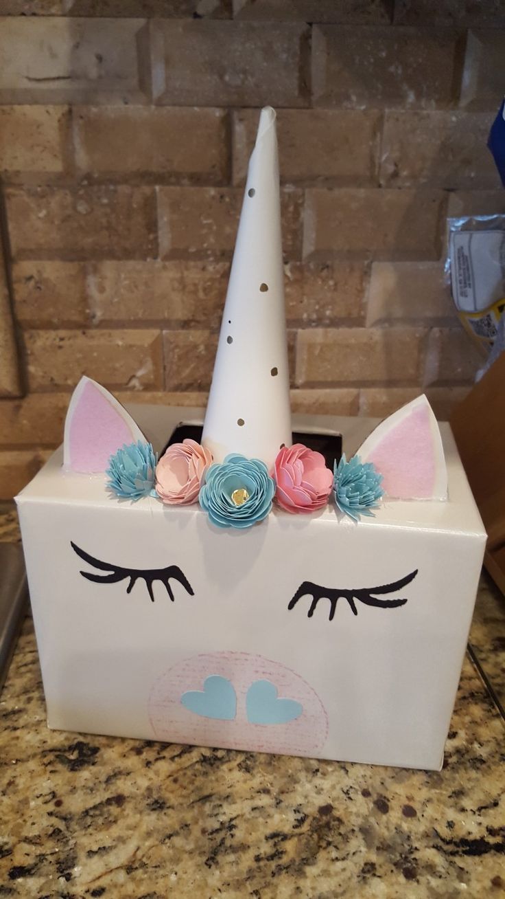 a white box with a unicorn face and flowers on it sitting on a counter top