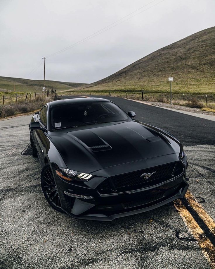 a black mustang parked on the side of the road