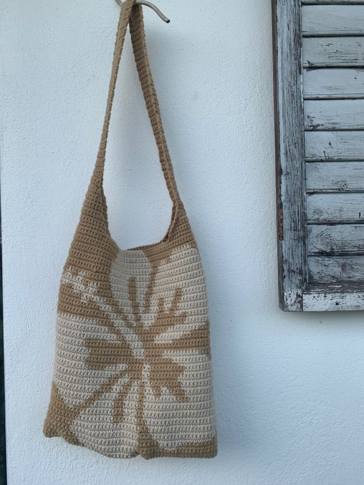 a crocheted bag hanging on the wall next to a window with shutters