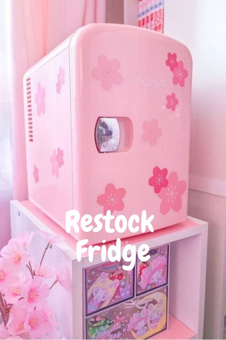 a pink toy refrigerator sitting on top of a shelf next to a vase with flowers