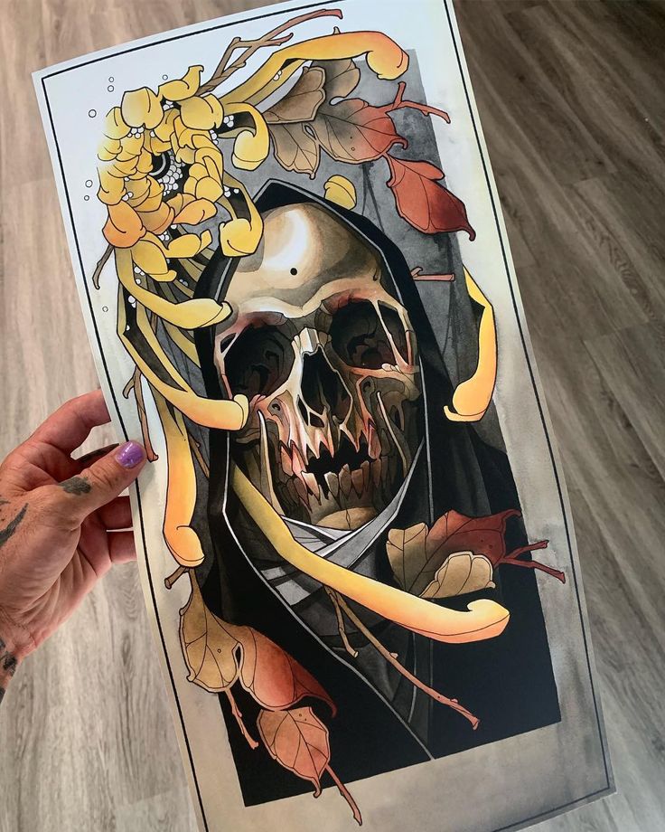 a person holding up a poster with a skull and flowers on the bottom half of it