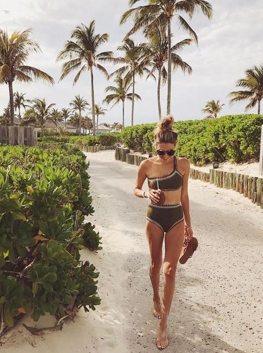 a woman in a bathing suit walking down a path with palm trees on either side