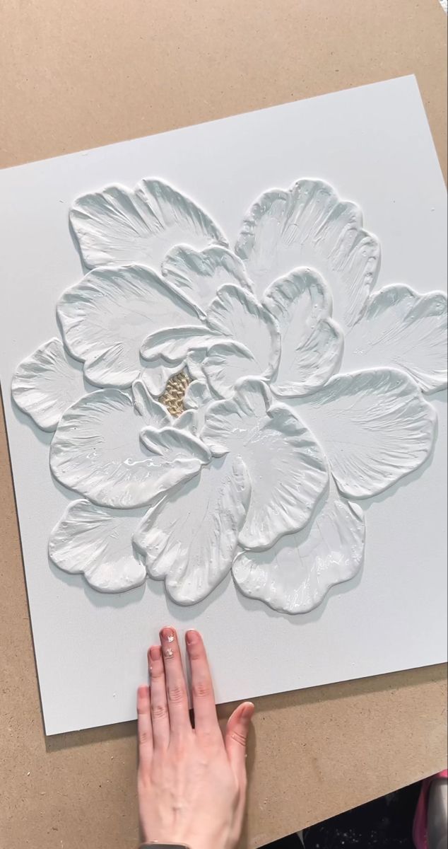 someone is working on an art project with white paper and gold foil flowers in the middle