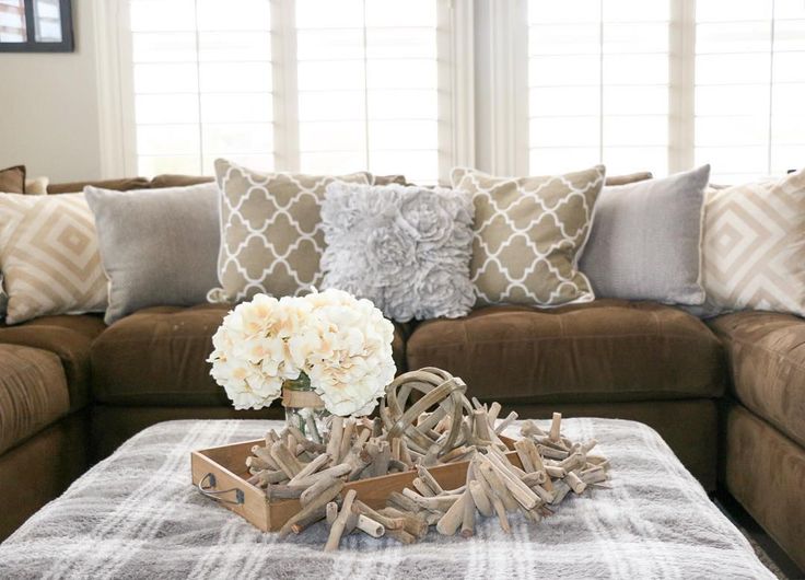 a living room filled with furniture and flowers on top of a coffee table in front of a window