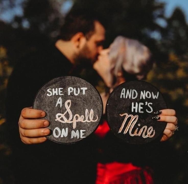 a man and woman kissing while holding signs that say she put a spell on me