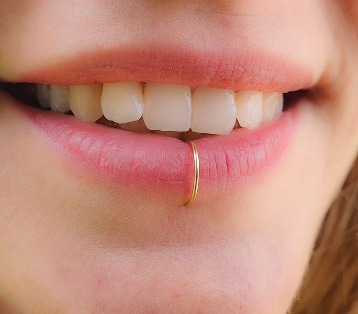 a close up of a woman's mouth with a ring on her nose and teeth