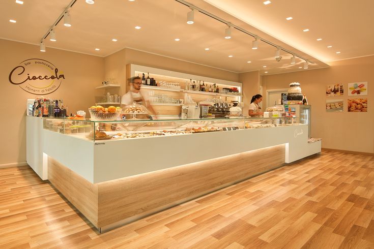 a person standing behind a counter with food on it in a room that has wooden floors