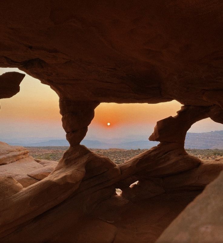 the sun is setting through an opening in some rocks that look like they have been carved into