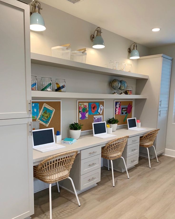 an office with two desks and three laptops on the same desk in front of a refrigerator