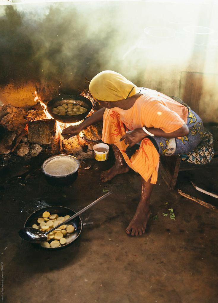 a woman cooking food over an open fire