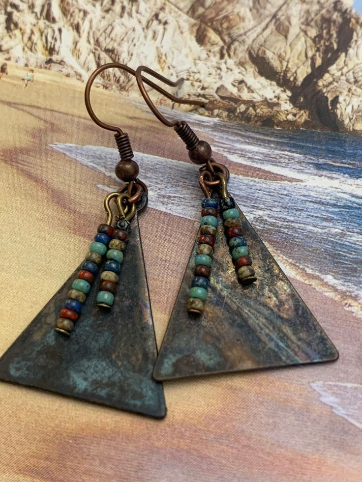 Copper and Glass Earrings. Triangular copper metal that has patina finish. Tiny earth multi-colored Czech glass beads adorn and dangle on the front. Unique handcrafted earrings. Sure to be your favorite pair! Highest Quality Craftmanship. Artisan Copper Beaded Earrings Nickel Free, Nickel-free Multicolor Copper Earrings, Multicolor Nickel-free Copper Earrings, Nickel-free Bronze Artsy Earrings, Nickel-free Bronze Beaded Copper Earrings, Unique Nickel-free Copper Beaded Earrings, Unique Copper Beaded Earrings Nickel Free, Earth Colors, Metal Forming