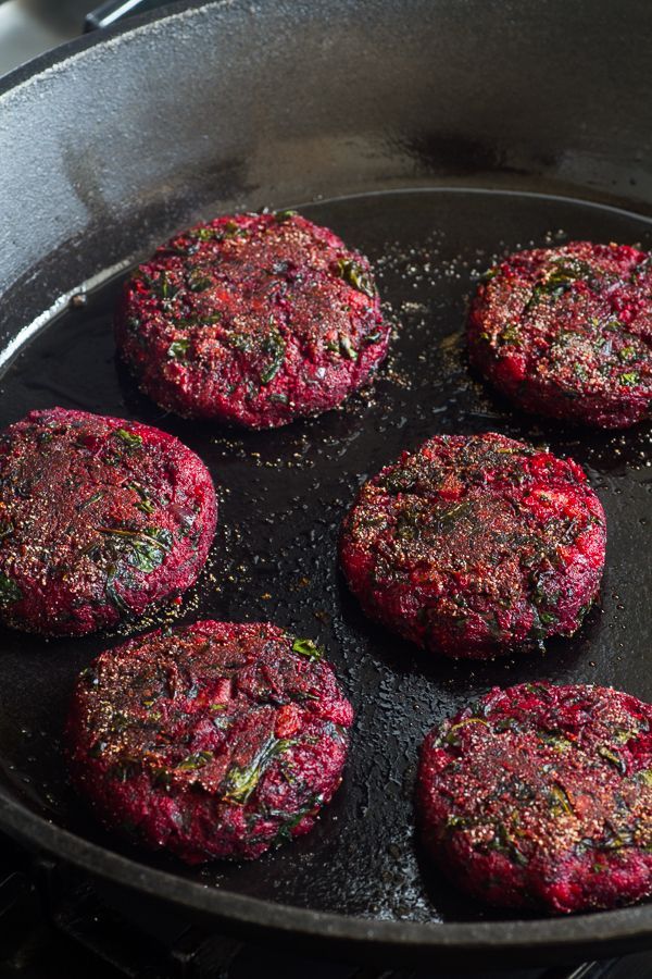 four hamburger patties cooking in a frying pan