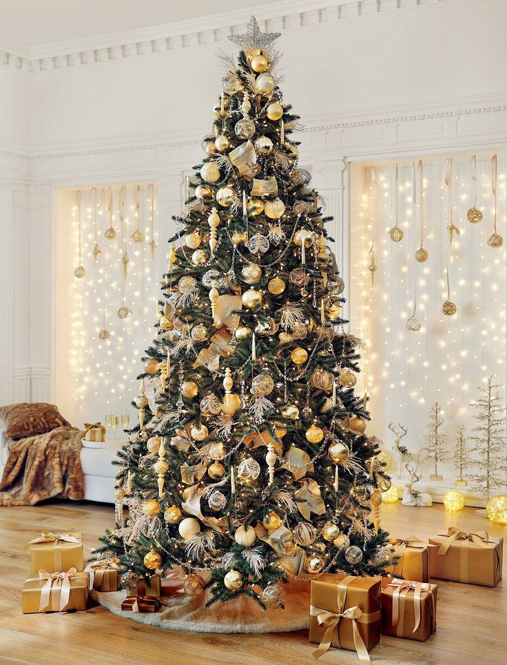 a decorated christmas tree with gold and silver ornaments in a room filled with presents on the floor