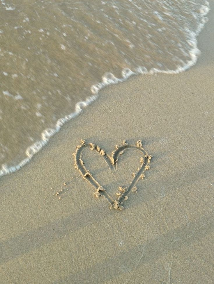 a heart drawn in the sand at the beach