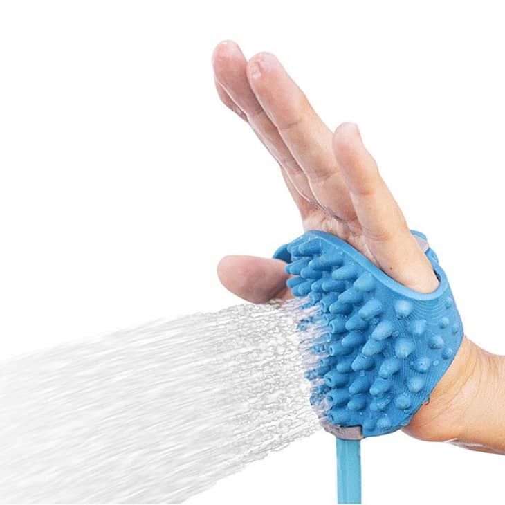 a person's hand holding a blue scrubber with water coming out of it