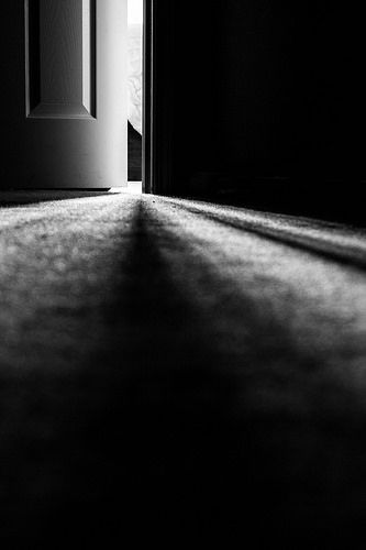 an open door in a dark room with light coming through the doorway and shadows on the floor