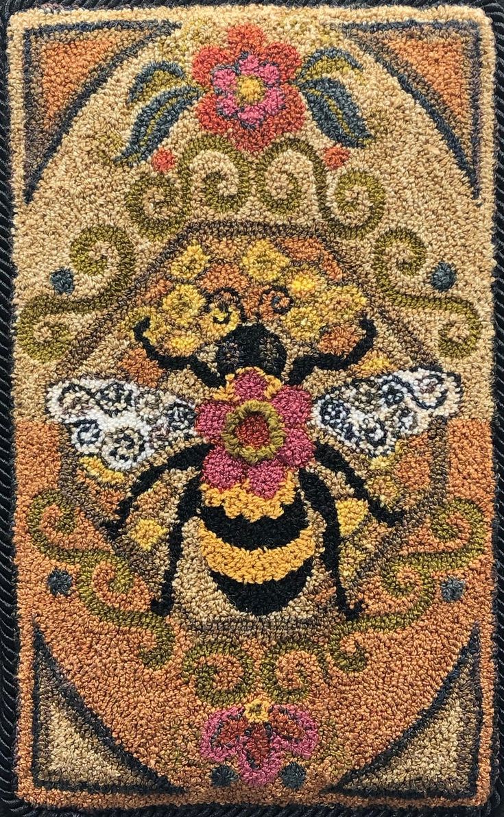 a close up of a rug with a bee and flowers on the front, surrounded by black background