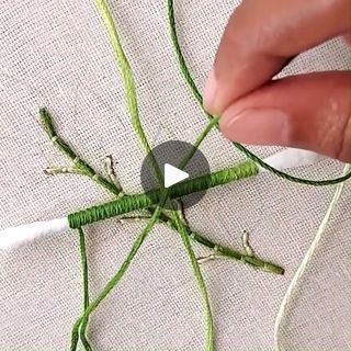 someone is working with green string and thread on a piece of fabric that has been stitched together